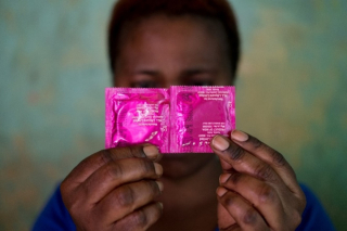 A sex worker conceals her face with a pack of condoms in the Katosi fishing village in Mukono, located east of Kampala, Uganda’s capital (October 24, 2019). Credit: E. Echwalu, UNAIDS, CC-BY 4.0 / Une travailleuse du sexe dissimule son visage derrière des emballages de préservatifs dans le village de pêcheurs de Katosi, dans le district de Mukono, à l’est de Kampala, la capitale de l’Ouganda (24 octobre 2019). Photo : E. Echwalu, UNAIDS, CC-BY 4.0 
