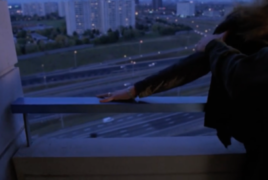 Person on balcony watching over highway.