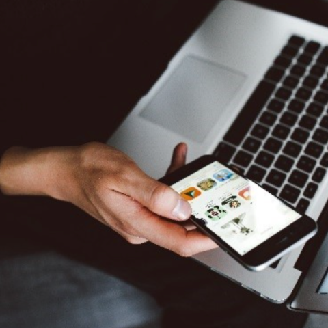 hand holding phone and laptop