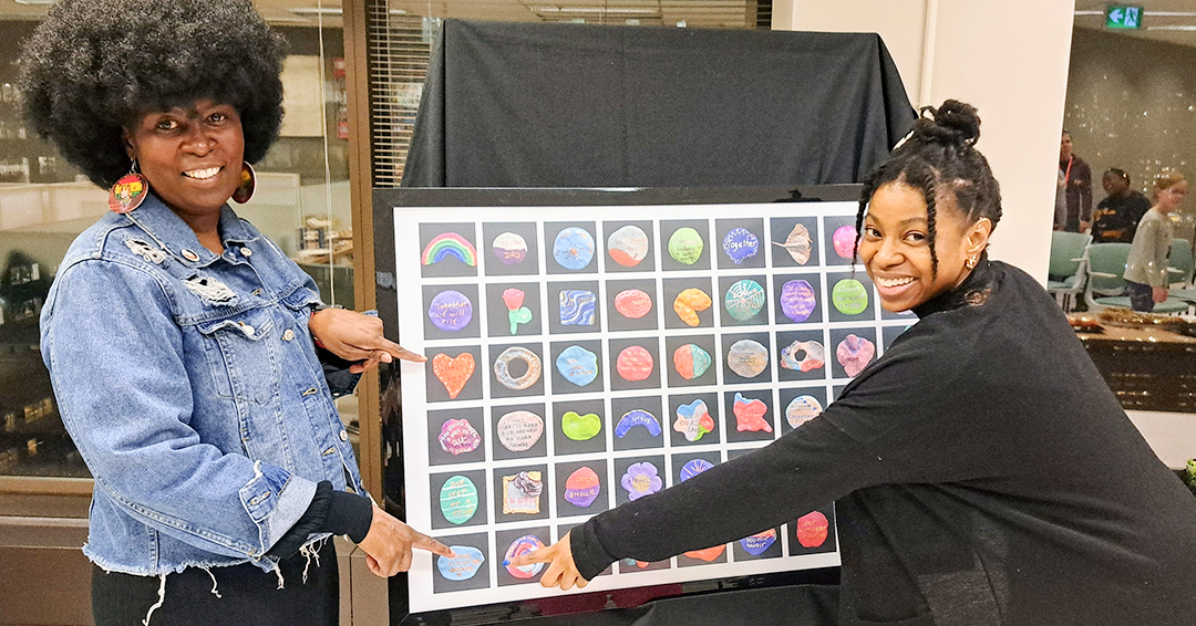 Two embers of the Côte-des-neiges Black Community Association admire a photo collage of the rock art project created with Ingram School of Nursing students.