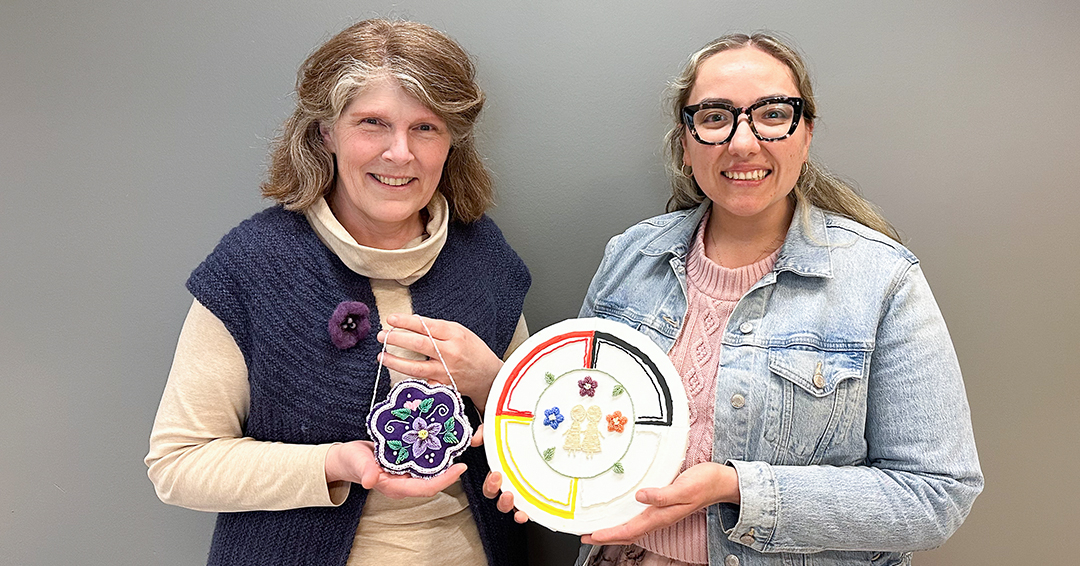Erin Patton holds her NUR2-608 art installation assignment, her first beading project, while Heather Hart holds a gift made by Erin.