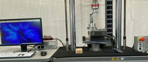 Computer monitor, keyboard, and mouse on table beside the Instron ElectroPuls Dynamic Test instrument