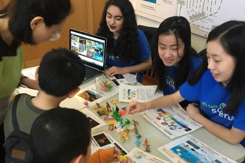 Three Let's Talk Science volunteers teaching a mother and her children about marine mammals