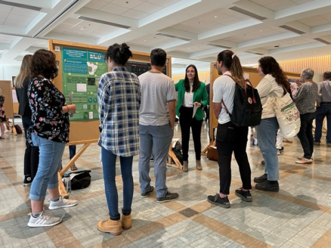 Student presenting their poster to a crowd