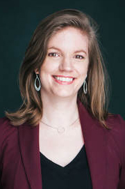 Head-shot of a smiling professor Natalya Gomez, shoulder-length brown hair and earrings.