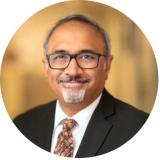 mature bearded man wearing glasses and suit smiling into the camera