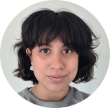 Young woman with short dark hair and eyes smiles into the camera