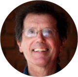Professor Richard Koestner wearing wire-rimmed glasses smiles joyfully in head-shot.