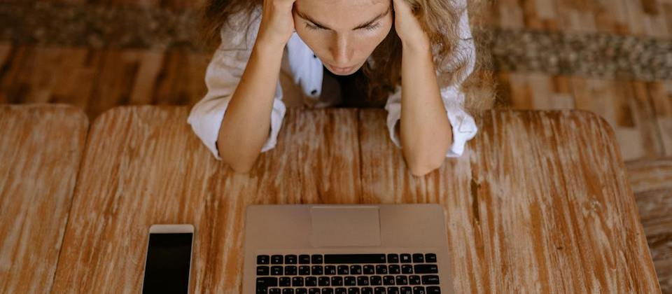 Woman Looking Upset in Front of Silver Laptop