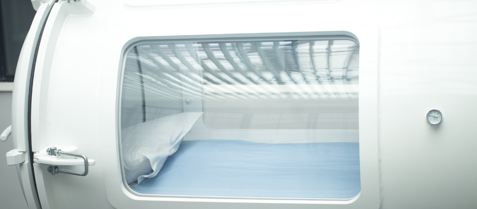 Hyperbaric chamber with a window and pillow inside.