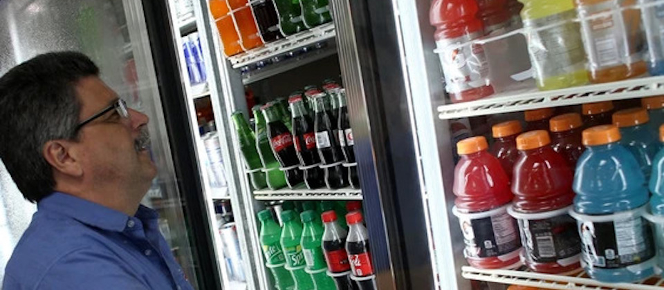 Person looking at refrigerator with various sport and soft drink options