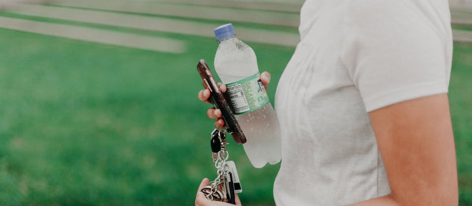 person holding bottled water and car keys