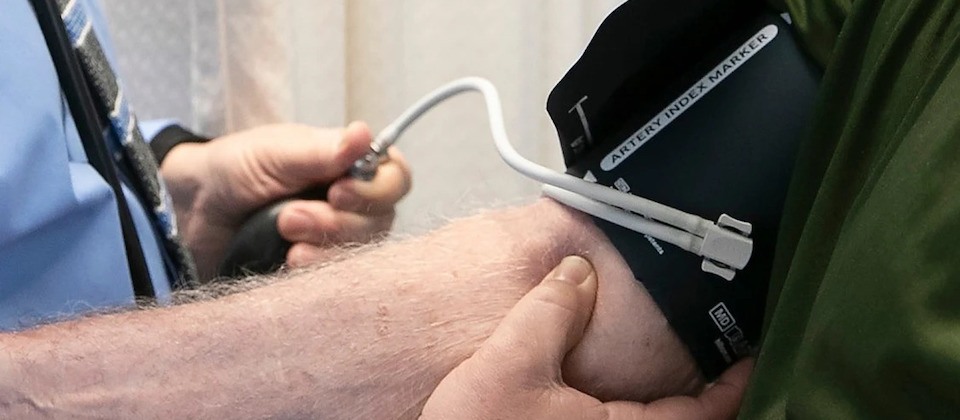 clinician using a blood pressure cuff on a patient