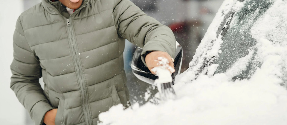 person cleaning snow off car hood