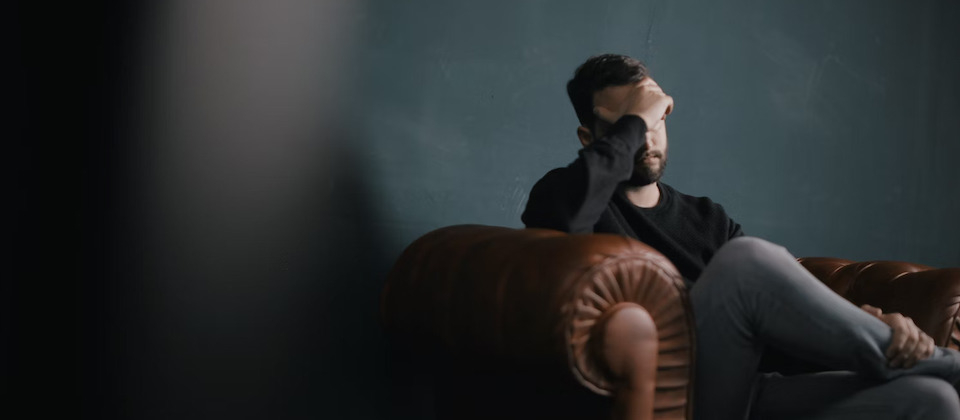 man sitting on couch with headache