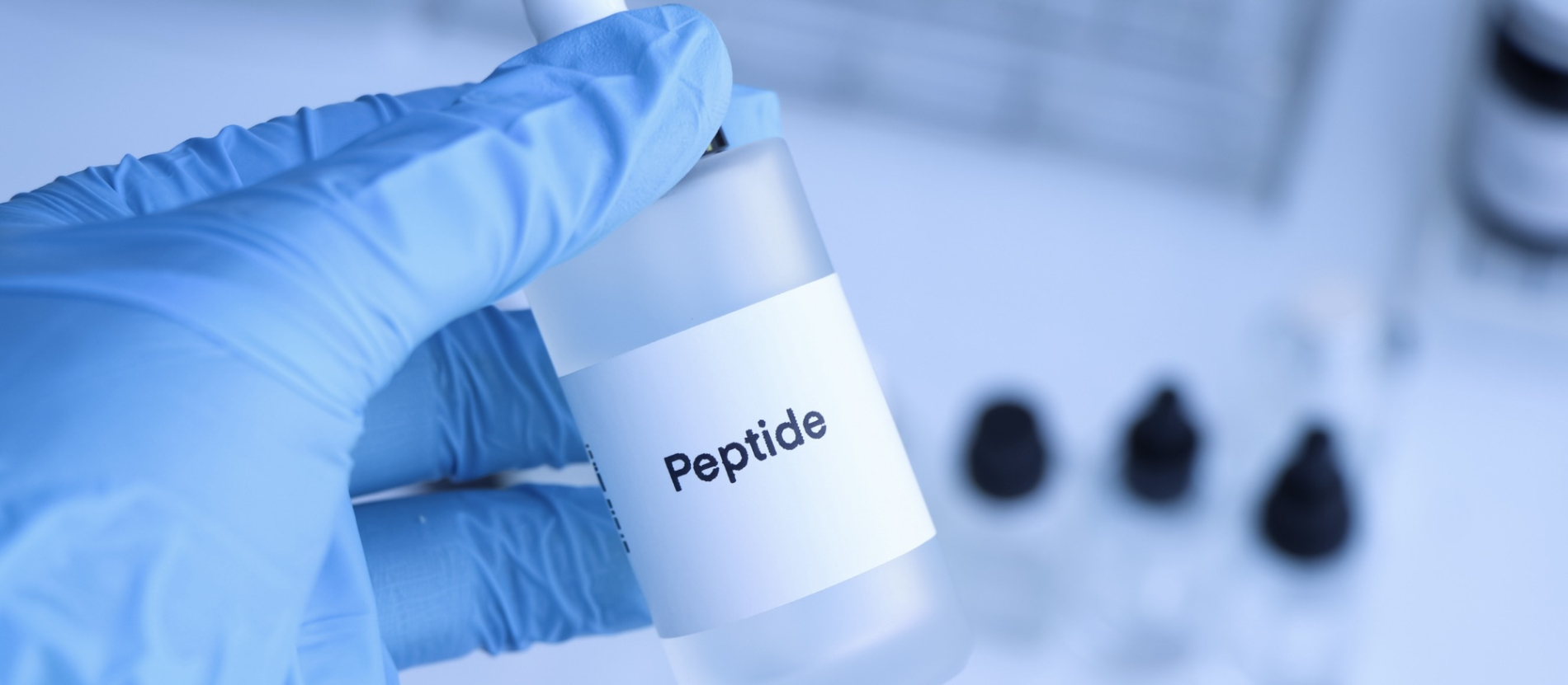 gloved hand holding a clear bottle labelled "peptide"