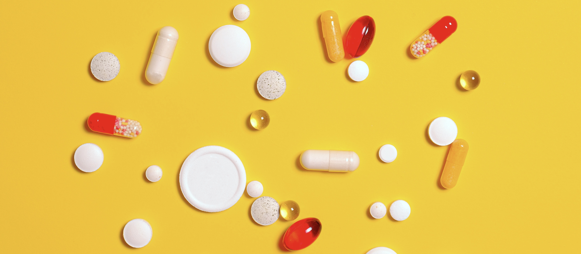 Various pills and medications on a yellow background.