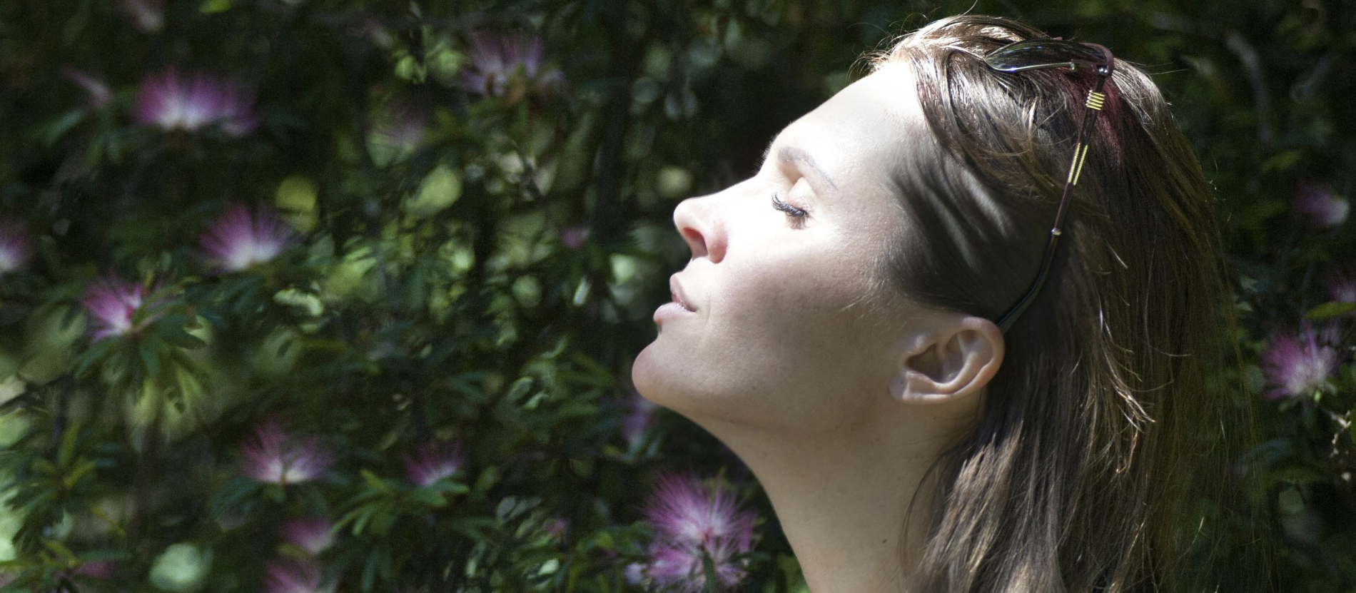 Brunette woman tanning her face in the sun.