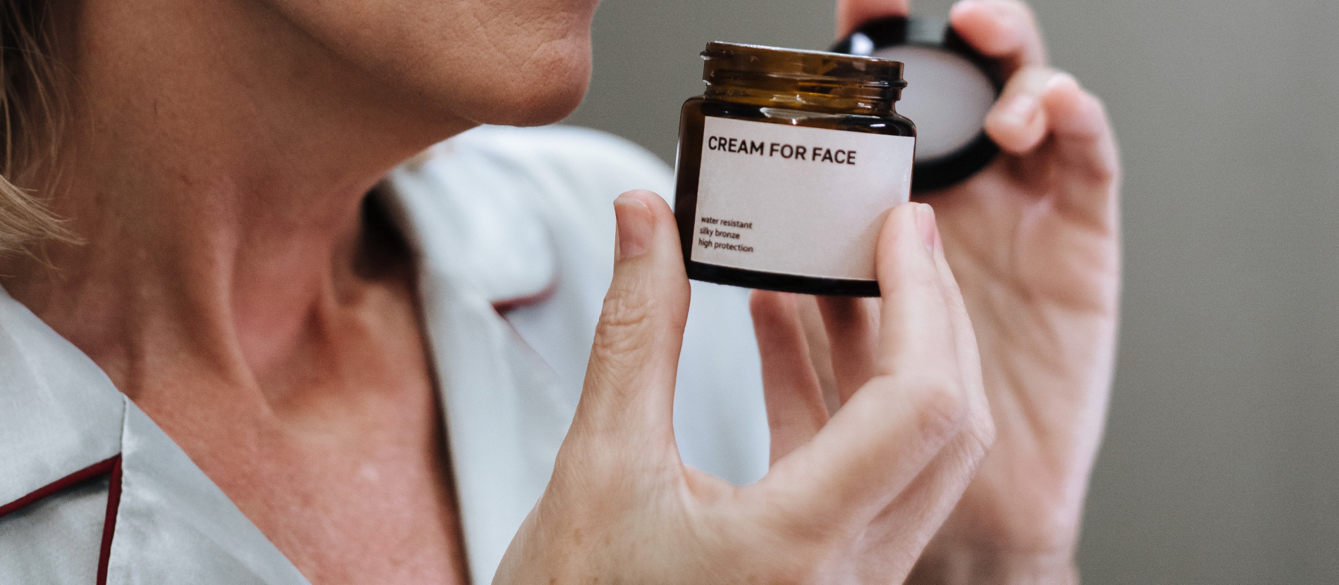 woman holding up a bottle that says "face cream"