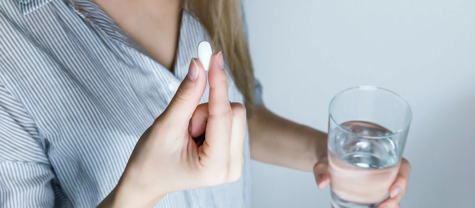 woman taking a pill with some water