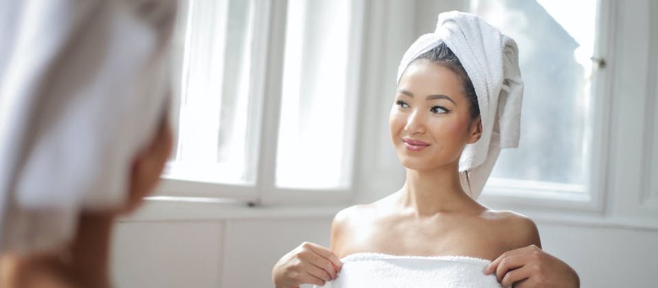 Woman in White Towel Standing in Front of the Mirror