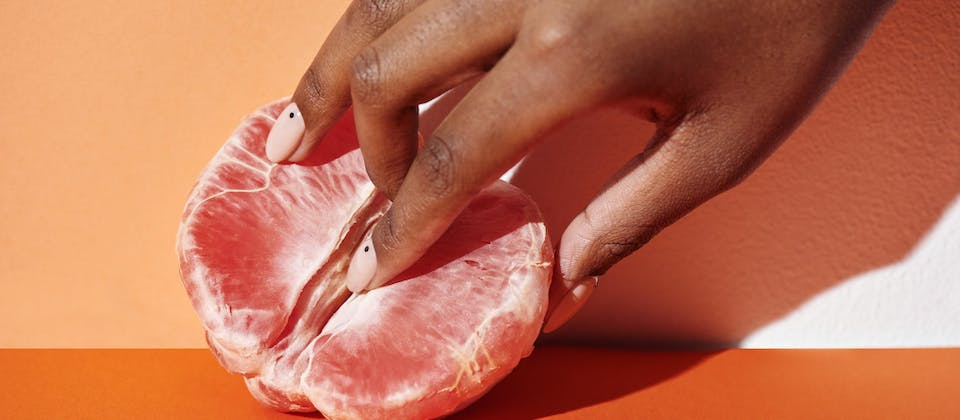 A Close-up Shot of a Person Touching a Grapefruit