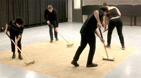 people pushing sand around on the floor with brooms