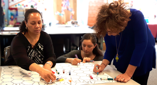 three people working on art at a table