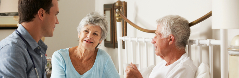 Young doctor in at-home visit advising wife and husband (who is bed bound)