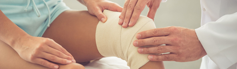Pediatric surgeon with young patient with bandaged knee