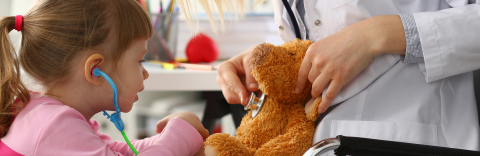 Child with toy stethoscope and teddy bear