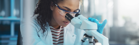 Female researcher looking through microscope