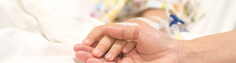 Closeup of adult hand holding hand of sick child