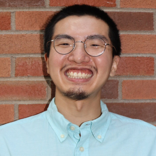 A man in a blue shirt and glasses smiling