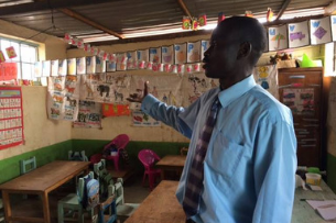 A teacher stands in the foreground of an elementary classroom
