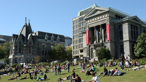Des étudiants se détendent au soleil sur la pelouse devant la bibliothèque Redpath sur le campus de McGill