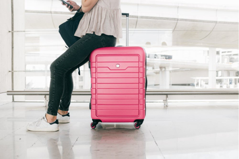 woman sitting on pink luggage 