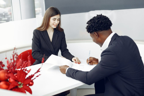man and woman signing contract at desk