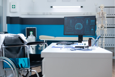 Empty modern hospital office room equipped with medical professional equipment ready for patient consultation. Computer standing on table having human body skeleton on screen.