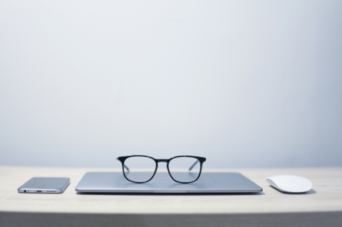 Pair of glasses resting on top of a closed laptop computer