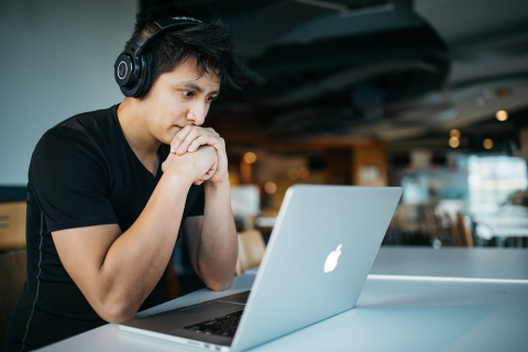 Man wearing headphones looks at computer
