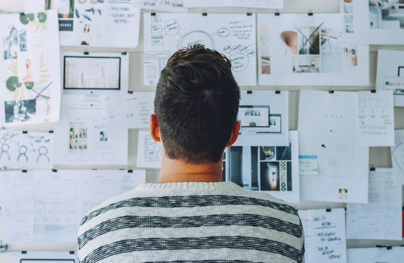 A man observing papers on a wall