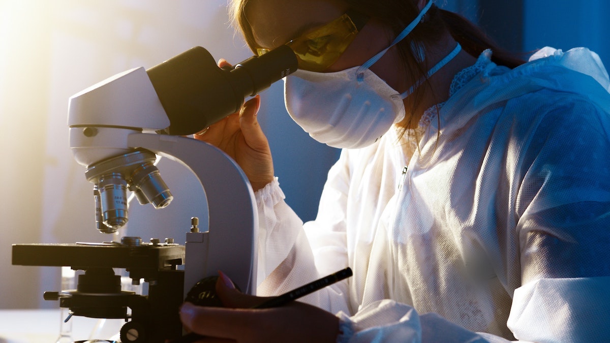 lab technician looking into a microscope.