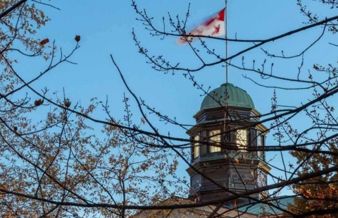 McGill Arts building and flag seen through autumn trees