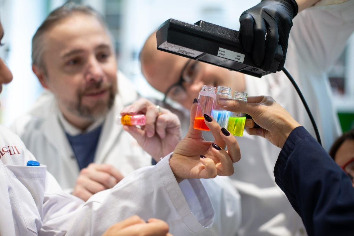 Professor Tomislav Friscic examining colourful vials with students.