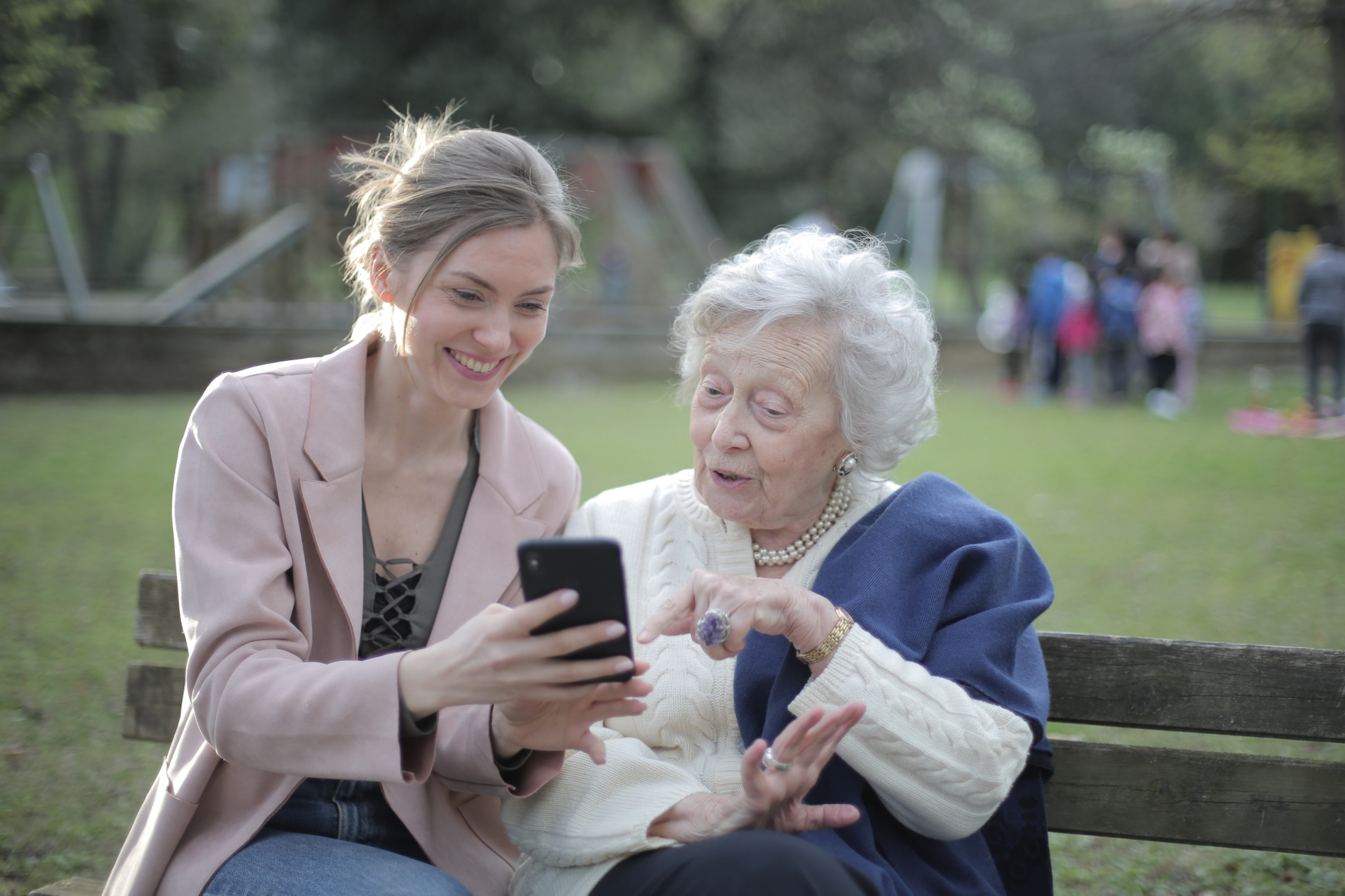 a woman showing an elderly woman something on a cell phone