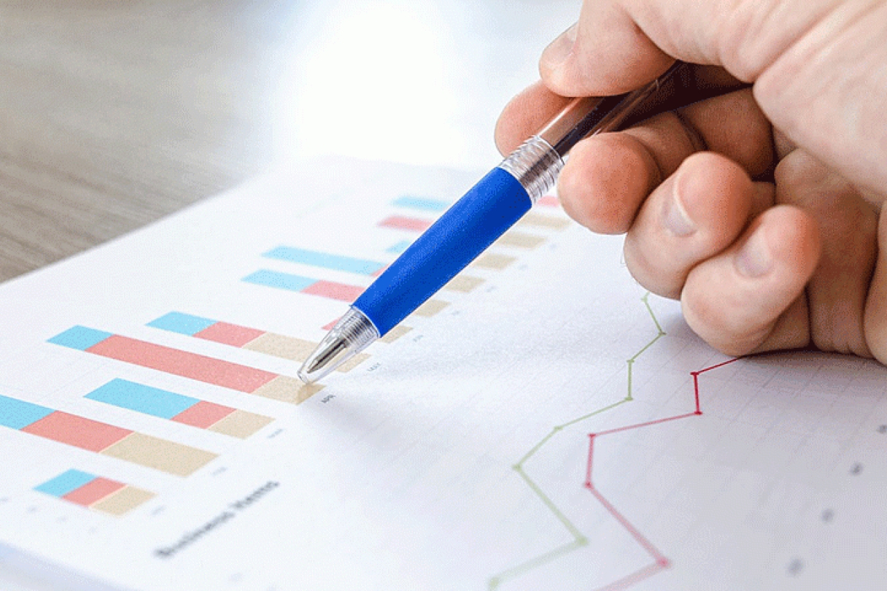 a hand holding a blue pen to a business chart.