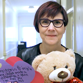 Professor Cindy Blackstock smiling at the camera, holding a teddy bear and a pack of heart-shaped letters from children
