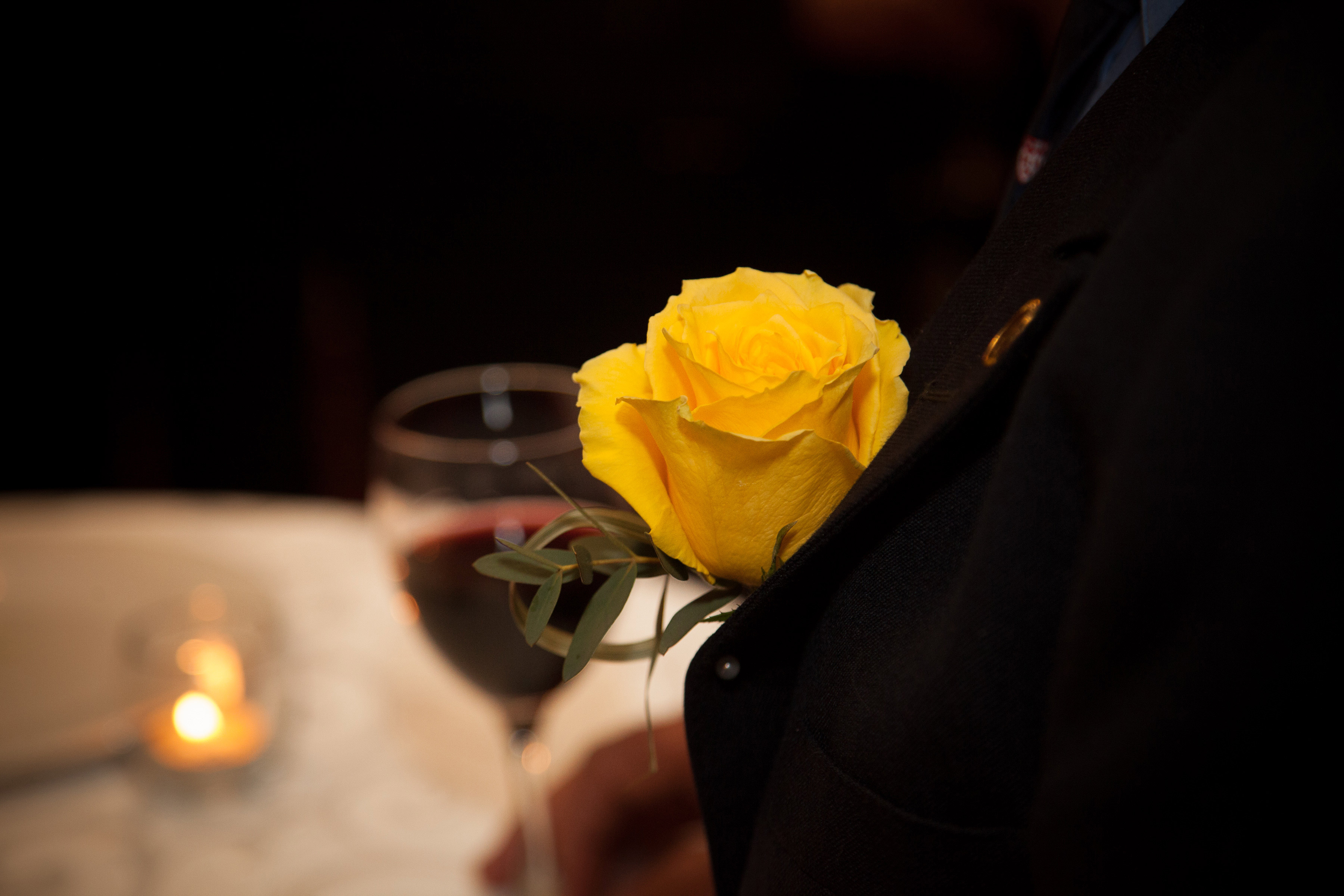 a close up shot of a yellow flower on a suit lapel