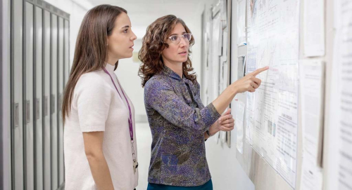 Two female scientists looking at a poster
